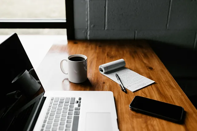 The image conveys a sense of productivity and focus, perhaps suggesting a writer or blogger’s workspace. The arrangement of objects on the table implies a sense of organization and intention.